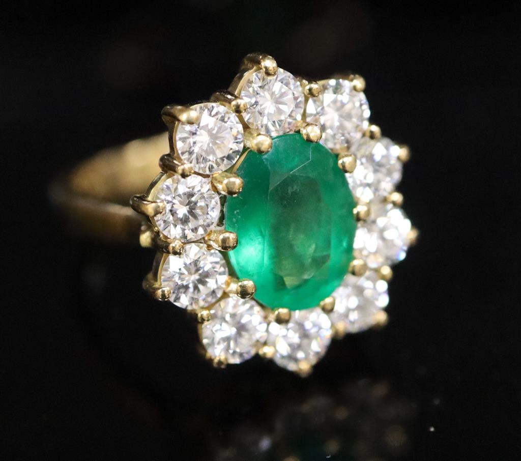 A modern 18ct gold, emerald and diamond oval cluster ring,